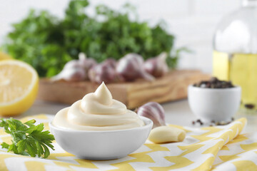 Tasty mayonnaise sauce in bowl and parsley on table, closeup. Space for text