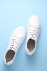 Pair of stylish white sneakers on light blue background, top view