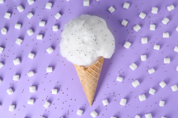 Sweet cotton candy in waffle cone surrounded by marshmallows on purple background, flat lay