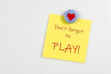 Magnet and yellow sticky note reminder to play on refrigerator
