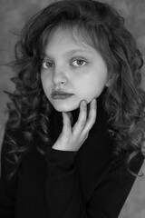 black and white photo of a beautiful brown-haired girl with big blue eyes with curls in a black turtleneck