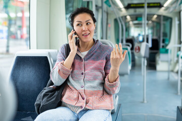 Oriental woman talking on a mobile phone while riding a tram