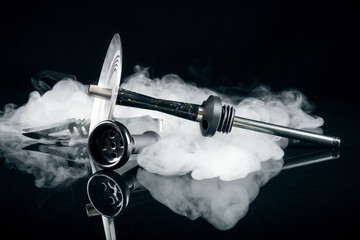 Hookah with bowl and tongs on a black background. Artistic shooting in a studio with white smoke...