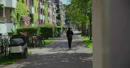 View of quiet residential street in calm neighbourhood in Copenhagen. Commuter city bikes parked next to entrance doors. Nice city life image. Green trees and facade plants on apartment building