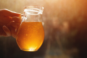 person holding transparent jug with natural golden honey