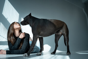 young beautiful female play with staffordshire terrier dog at home