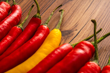 bunch of red and yellow pepperoni chili peppers on wooden background