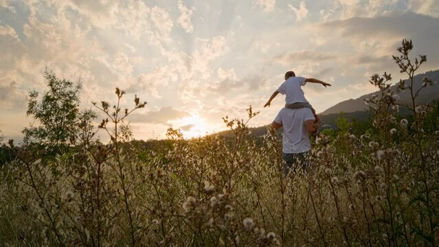 Father and son spend time together in nature on a summer evening in the rays of the setting sun. The love and family relationship of fathers to sons is very important.