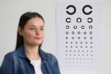 Young woman against vision test chart, selective focus