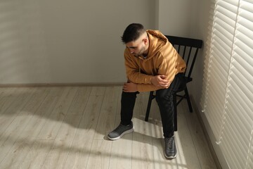 Sad man sitting on chair near window. Space for text