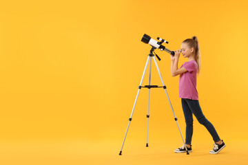 Cute little girl looking at stars through telescope on orange background, space for text