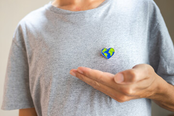 Earth Day: heart-shaped Earth pin proudly worn on a person's chest, emphasizing love for our planet and the call to preserve it