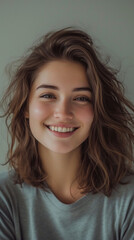 Headshot Portrait of a happy girl , her hair in a stylish lob, smiling at the camera. The background is a gentle taupe.