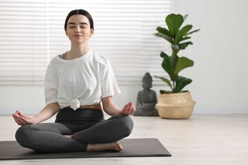 Beautiful girl meditating on mat in yoga studio