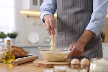 Making bread. Man preparing dough at wooden table in kitchen, closeup