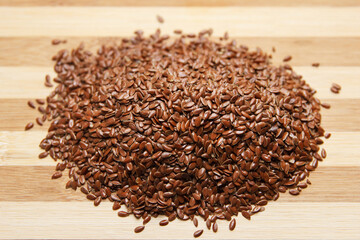 Many linen raw seeds lie on a wooden kitchen board. Raw baking ingredient.