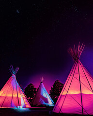 Teepees glowing colorfully at night under stars in Marfa, Texas © TomWindeknecht
