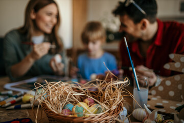 Parents and child engaged in a fun egg-painting session at the dining room