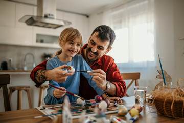 Dad and daughter bonding over a creative Easter egg decorating session, full of colorful paints and...