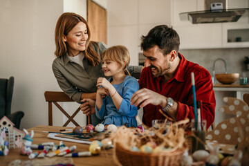 A family trio immersed in the Easter spirit, transforming plain eggs into works of art at the dining room table