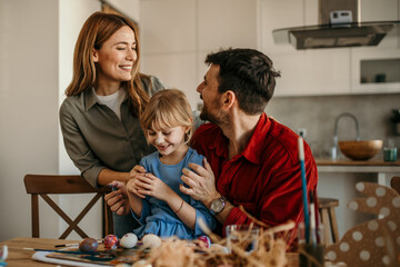 Parents and child joyfully engaged in the delightful task of painting eggs in their cozy dining space