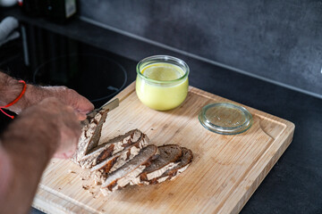 Selbstgemachte Vegane Butter zu Hause in der Küche ein mann schneidet brot in scheiben auf holzbrett