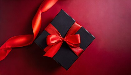 Black gift box decorated with red ribbon, view from above, isolated on red background, ideal for advertising products on Black Friday or Cyber Monday