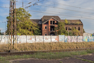Abandoned building separated from train tracks by graffitti covered wall - 728118385