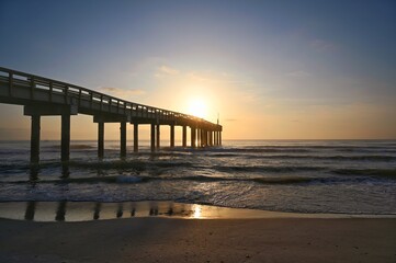 Sun rising at the end of fishing pier on the. Atlantic Ocean