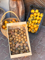 Fresh kiwi and persimmon fruits offered for sale directly from the farmer in boxes an baskets on the farm