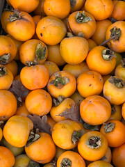 Background: fresh persimmon fruits offered for sale directly from the farmer in a box on the farm