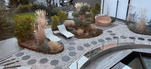 Modern garden design: two loungers idyllically surrounded by grasses and perennials, in the foreground round slabs laid in gravel and a barefoot path