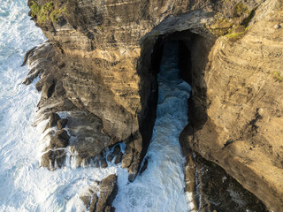 Rough seas and cave, Bethells Beach,  Auckland, New Zealand.