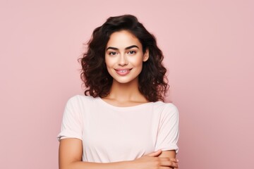 Portrait of a smiling young woman with long curly hair on pink background