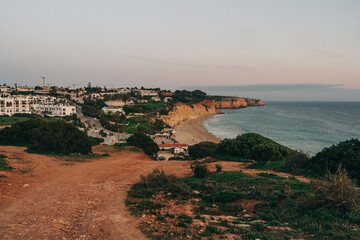 Picturesque sunset over cliffs and the ocean, with the silhouette of a city adding a touch of urban charm to the breathtaking natural landscape. Lagos, Portugal