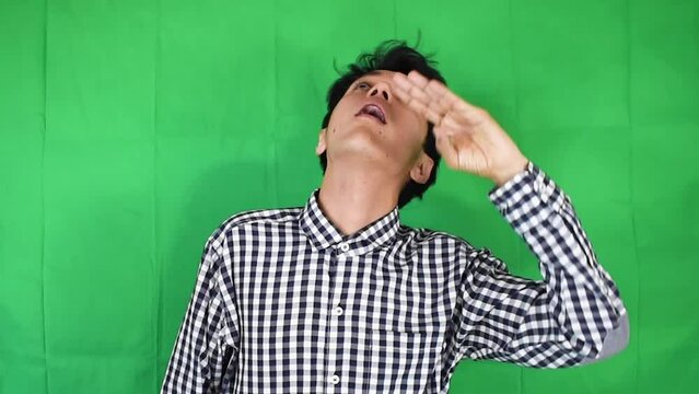 Joven hombre delgado mirando hacia arriba sobre un fondo verde