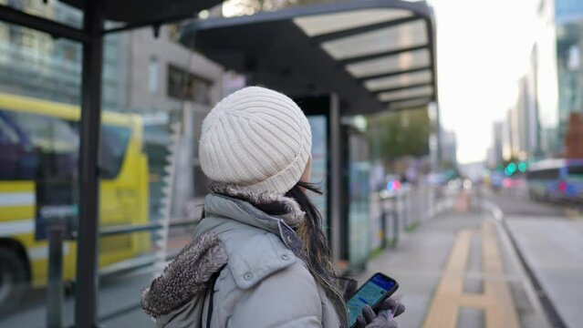 大韓民国ソウルの街なかのバス停でバスを待つ20代のフィリピン人女性 A Filipino woman in her 20s waiting for a bus at a bus stop in the streets of Seoul, South Korea