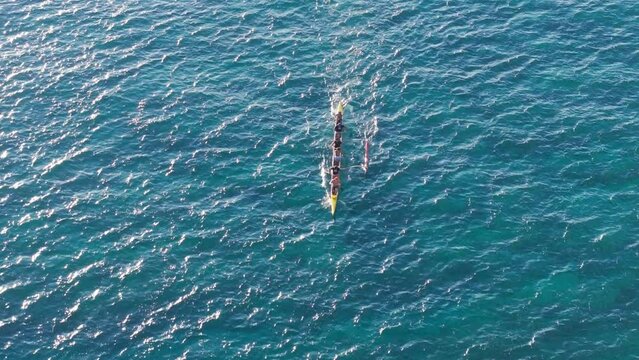 Water sport activity in scenic clear blue green ocean at summer. Top down shot of sports team sailing in outrigger canoe. Overhead view on athletic people boating the traditional Hawaiian Canoe, Oahu