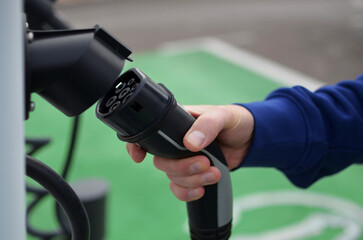 Close-up of a man's hand holding an electric car charger