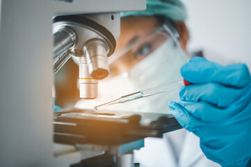 Fototapeta premium Female researchers are experimenting with pipette dropping a sample into a test tube in an experiment research in laboratory...
