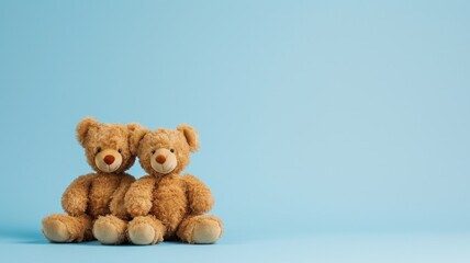 Two plush bears sitting together against a blue backdrop
