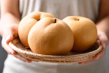 Asian pear fruit or Nashi pear in basket holding by hand