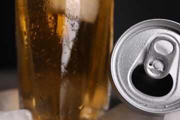 Energy drink in glass and aluminium can on black background, closeup