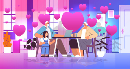 grandparents with granddaughter using laptop social media network valentines day celebration concept living room interior with pink love hearts