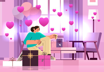 girl in love opening gift boxes in living room with pink air balloons in heart shape happy valentines day celebration concept
