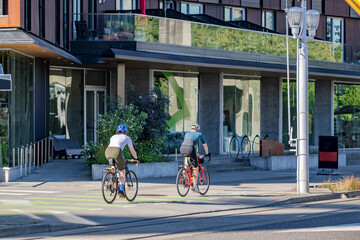 Man and woman as friendly married couple in sportswear in active recreation ride bicycles along a dedicated bike path along the street of modern city