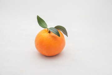 Ripe orange fruit and leaves on white background