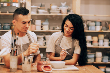 A young couple works in a pottery workshop. Painting a vase. The concept of hobbies, lifestyle and relationships.