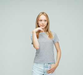 Young smiling blond woman wearing stripes t-shirt over light grey background.