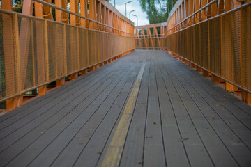 Obraz premium pedestrian wooden bridge, cyclist with orange metal structure, yellow signage